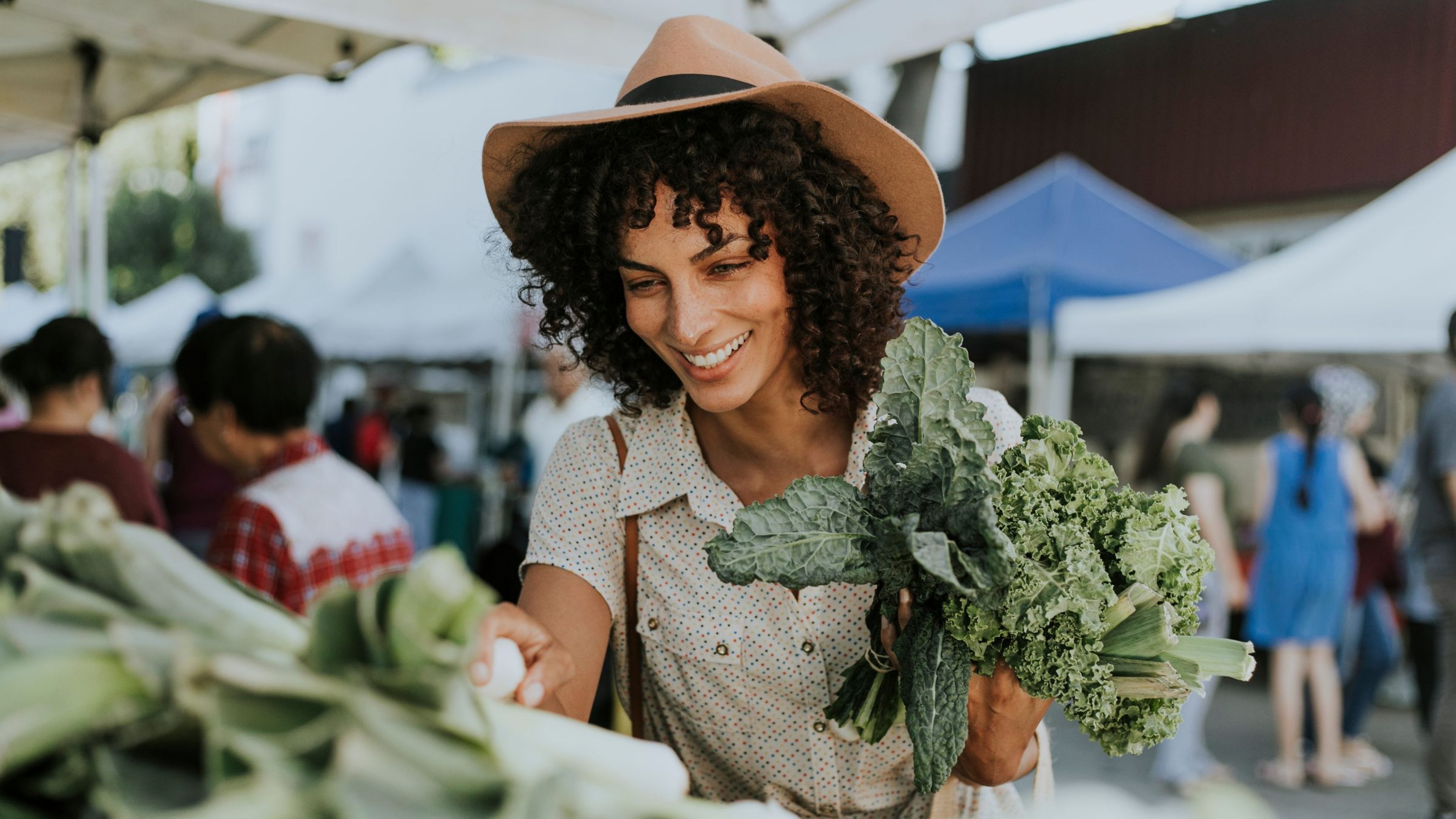 Smiling woman buying kale at a farmers market