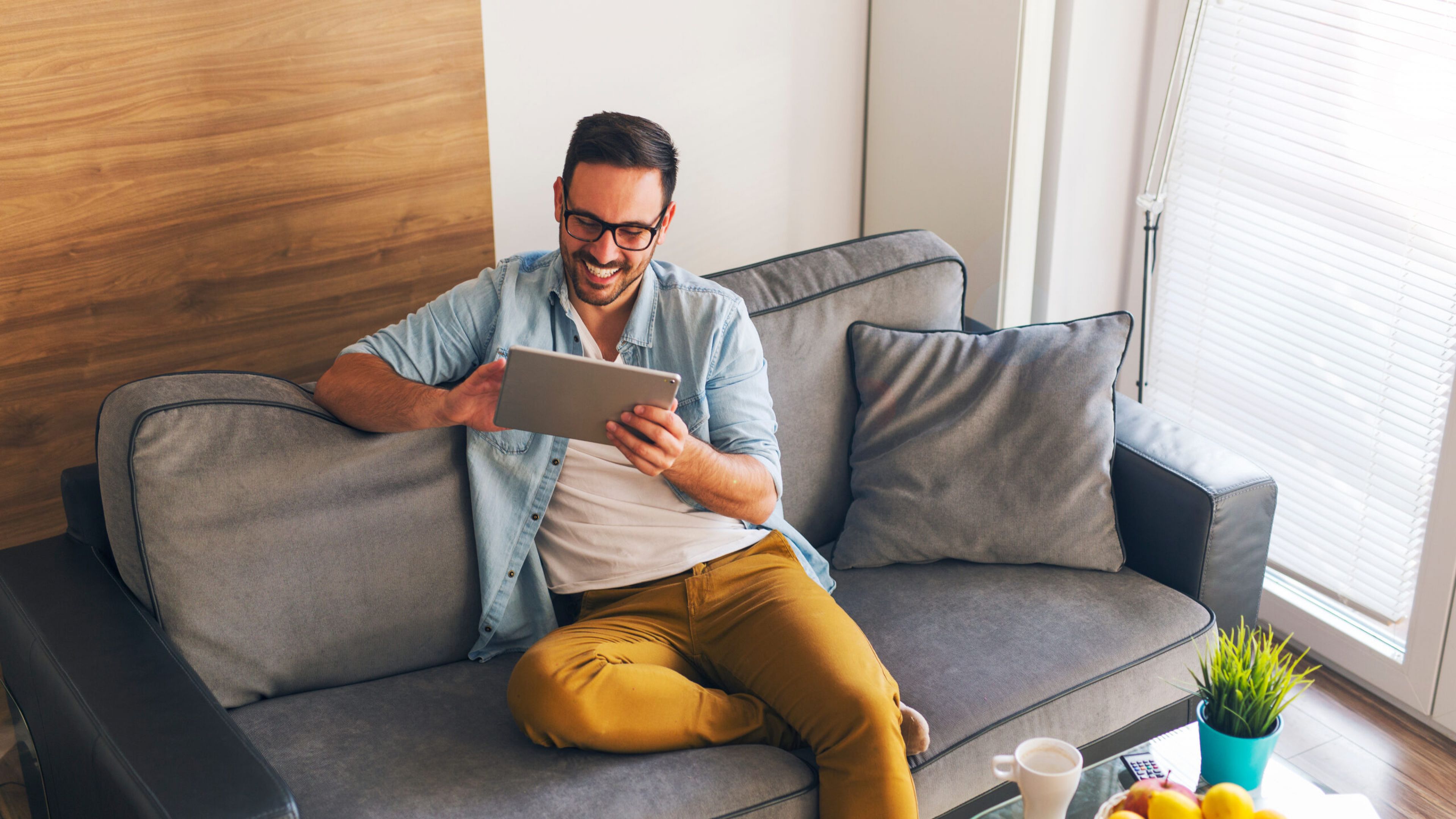 Smiling young man relaxing at home and using tablet