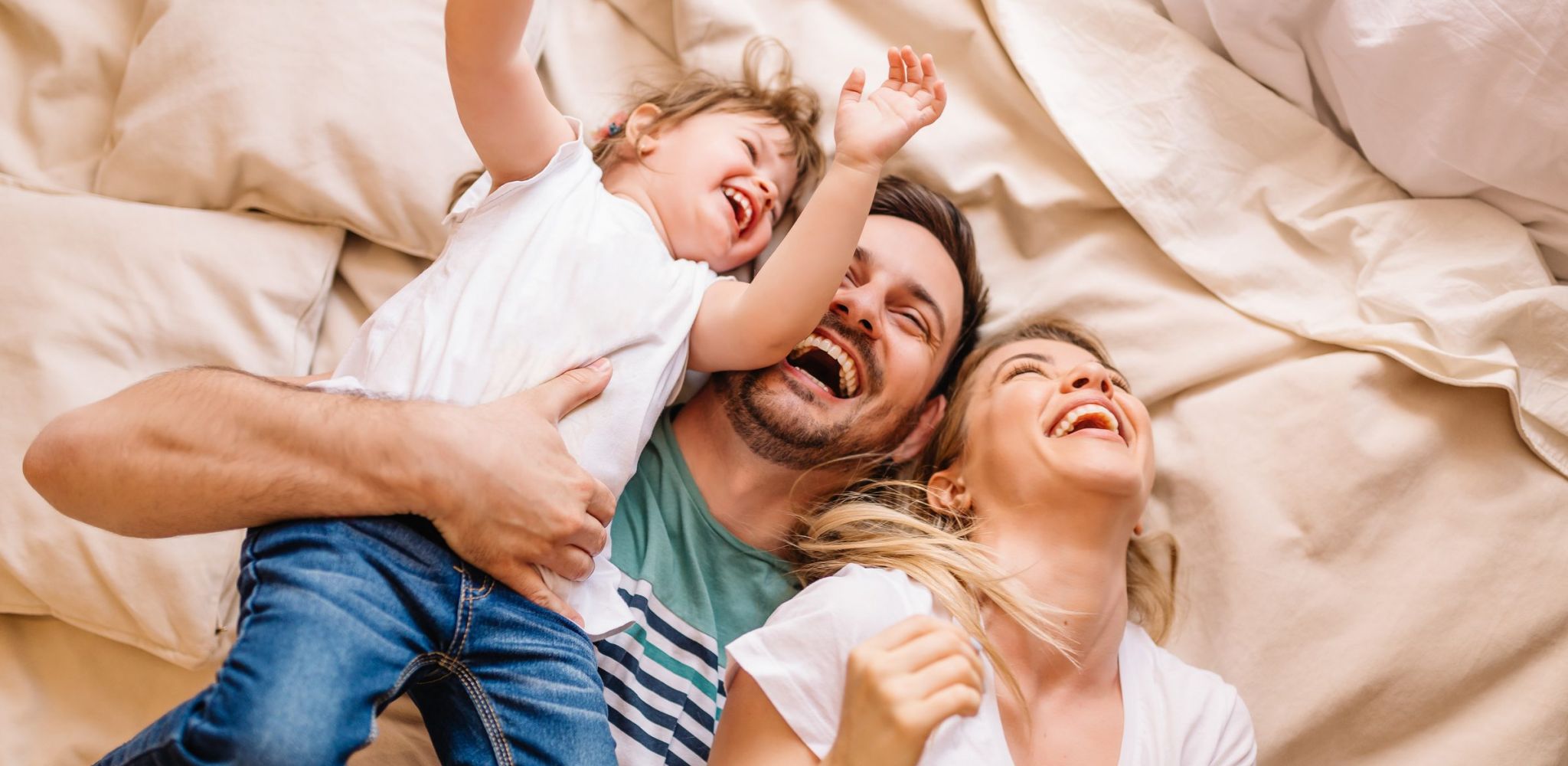 Happy family having fun in the bedroom while they lie on bed